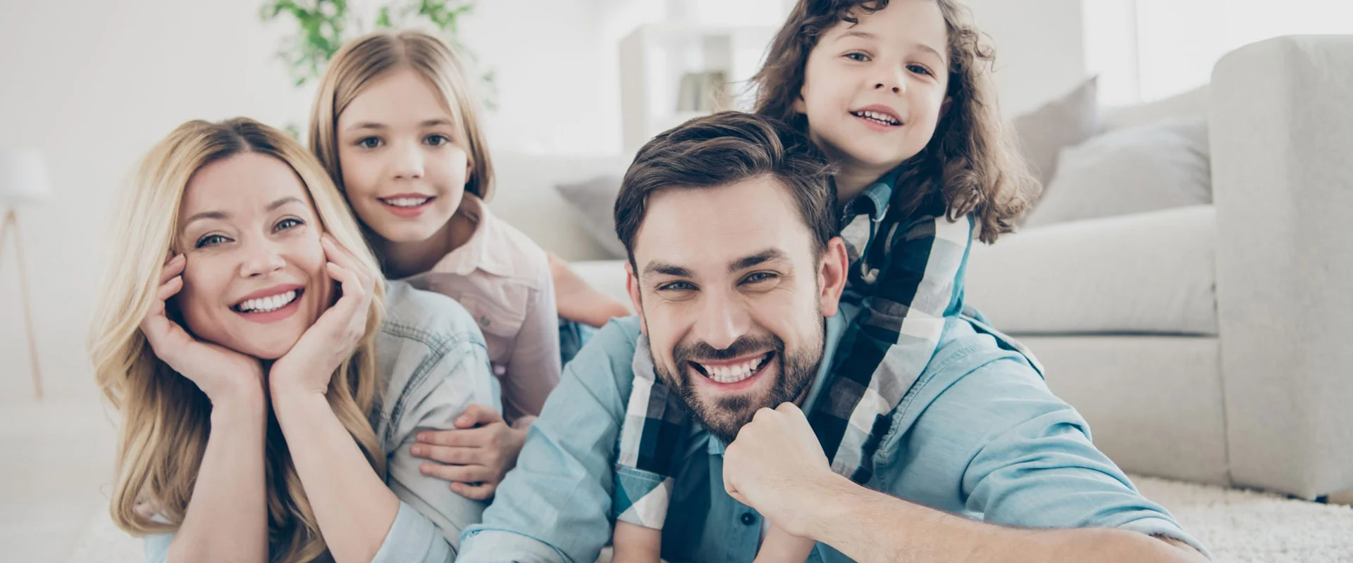 Smiling family of four relaxing on a living-room floor