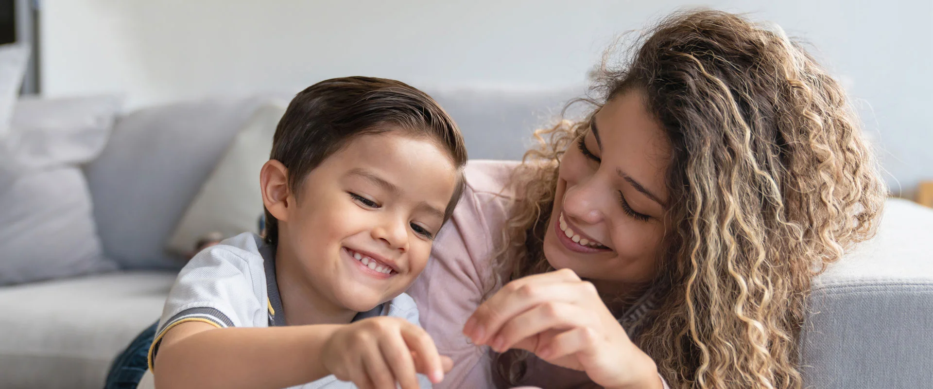 Mother and young son smiling together on a couch