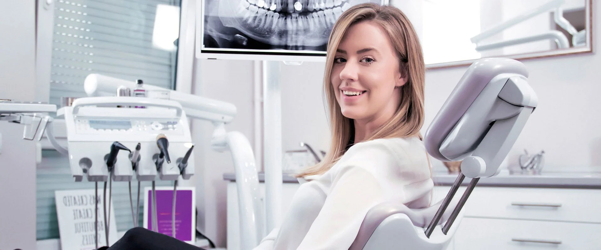 Smiling woman standing beside a dental chair